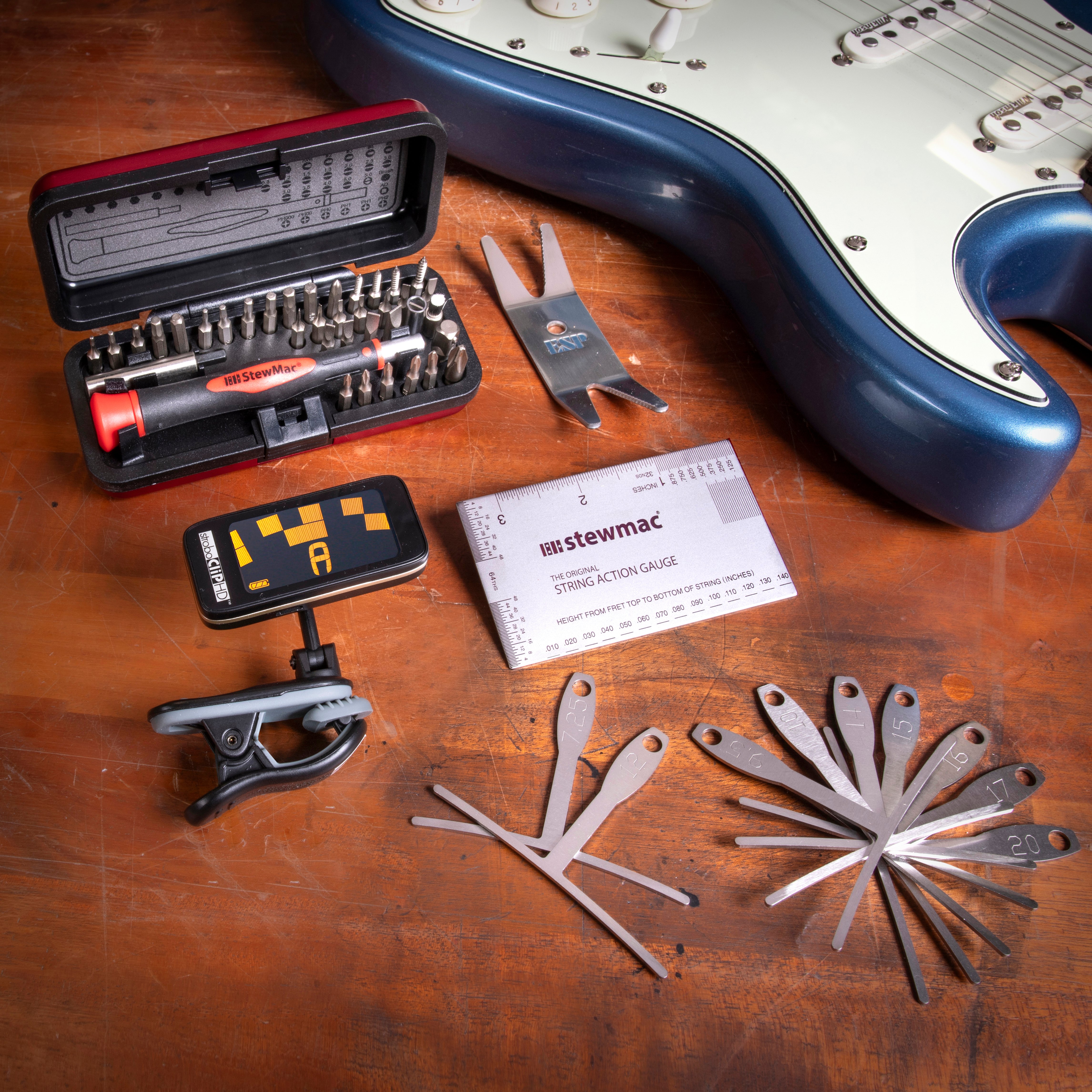 Werkzeuge, die bei der Gitarreneinrichtung auf der Werkbank mit blauer Stratocaster-Gitarre verwendet werden.