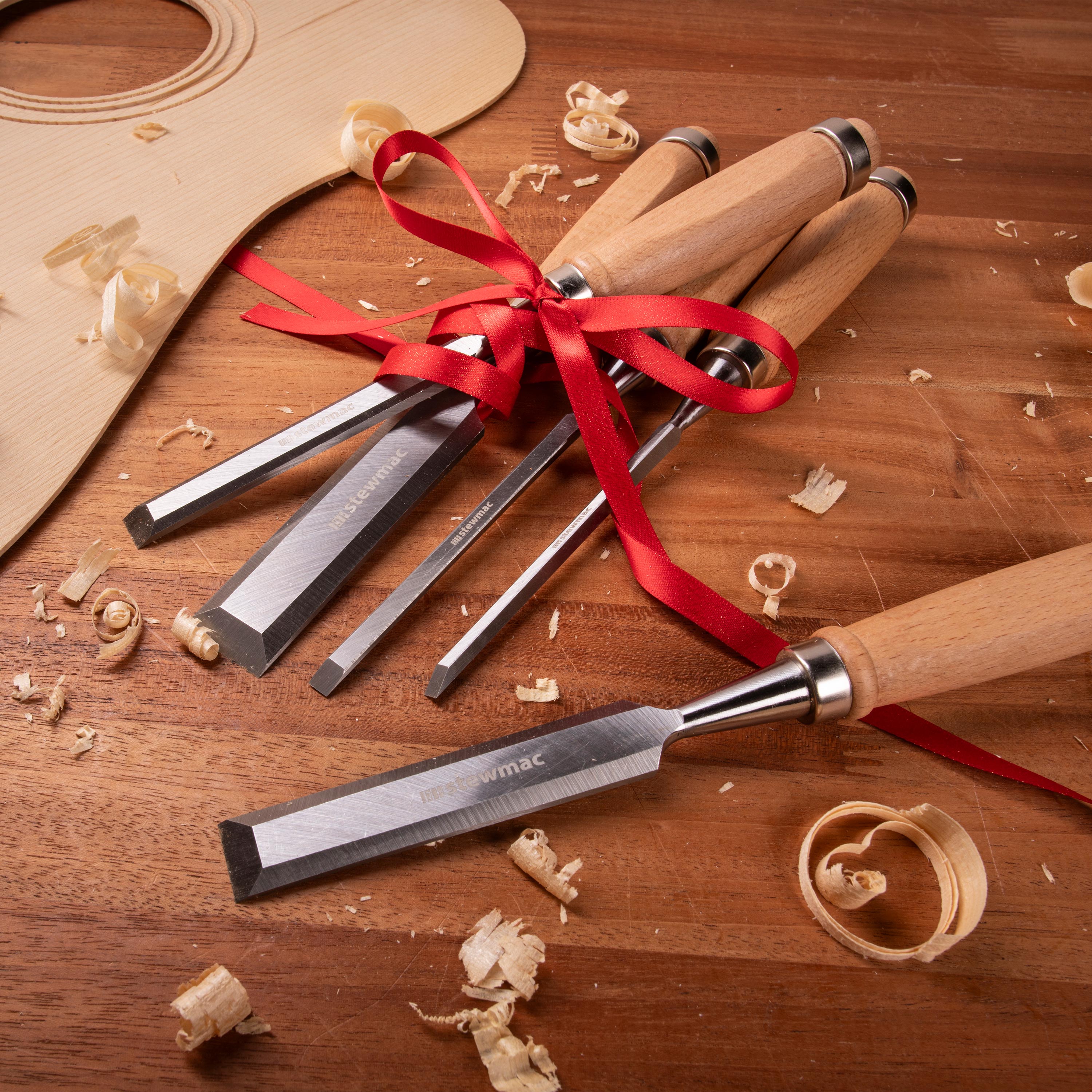 Set aus Holzmeißeln auf einer Werkbank mit Geschenkband.