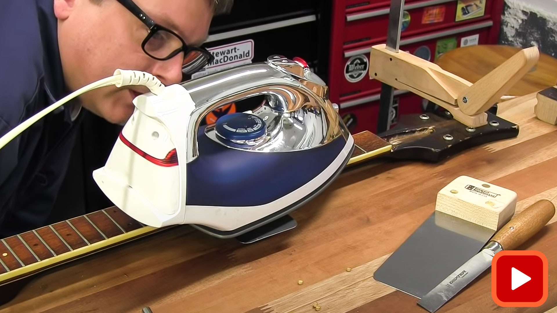 Mann, der Eisen verwendet, um Fretboard zum Entfernen zu erwärmen